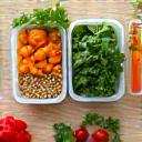 Vibrant, healthy meal prep containers arranged neatly on a wooden counter, symbolizing nutrition and organization